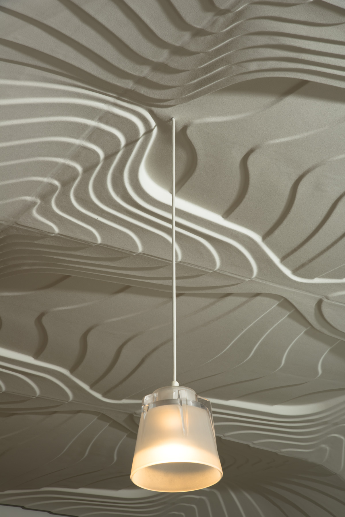Softly lit glass pendants hang from the sweeping gestural ceiling and complete the ambiance. 