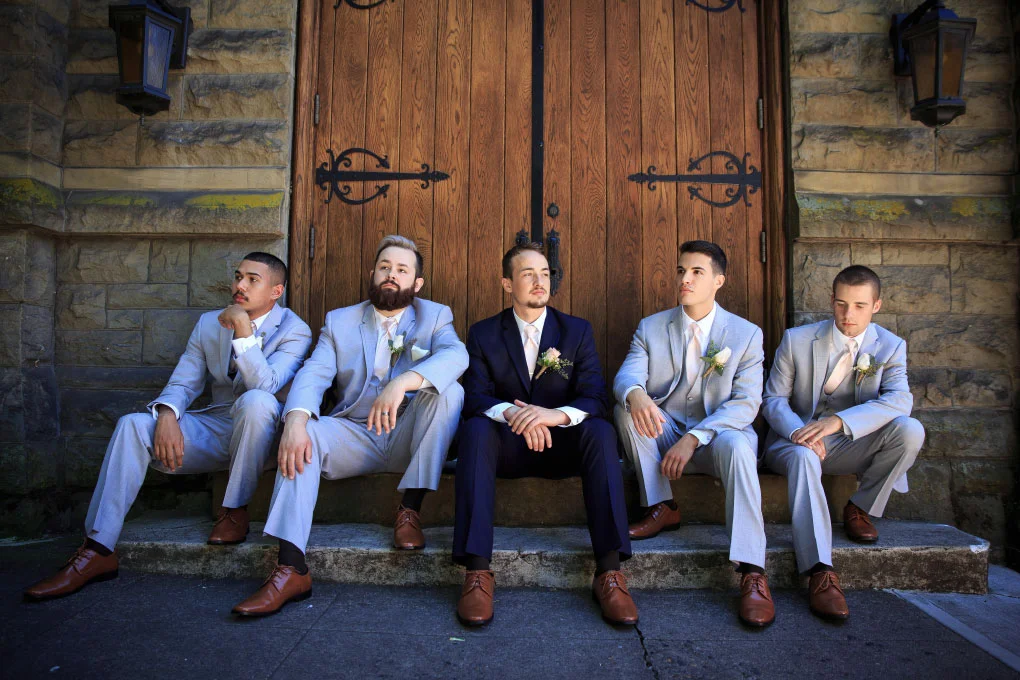 Groom with his groomsmen, sitting in front of a church door in Downtown Portland.