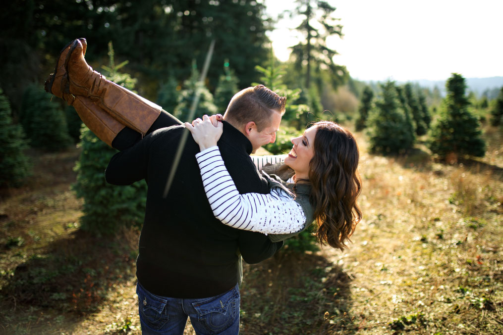 Man holding woman at Christmas tree farm.