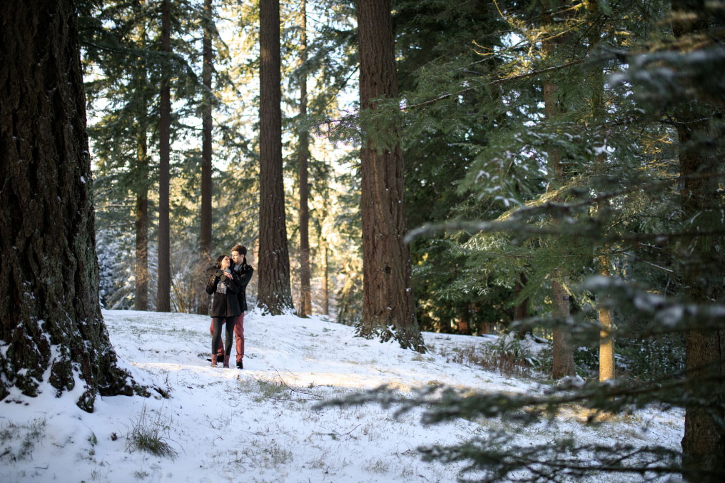 Man and woman holding each other in a snowy forest.