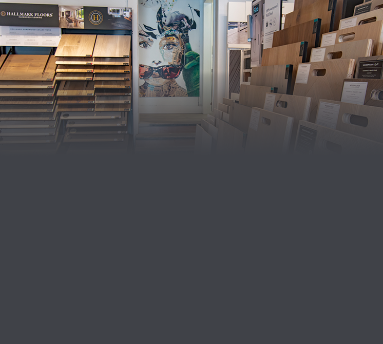 Display of flooring samples and catalogs inside a showroom, with a colorful artwork on the wall in the background.