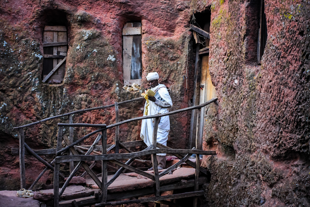 WORSHIPER studies holy scripture outside of a rock-hewn church in Lalibela