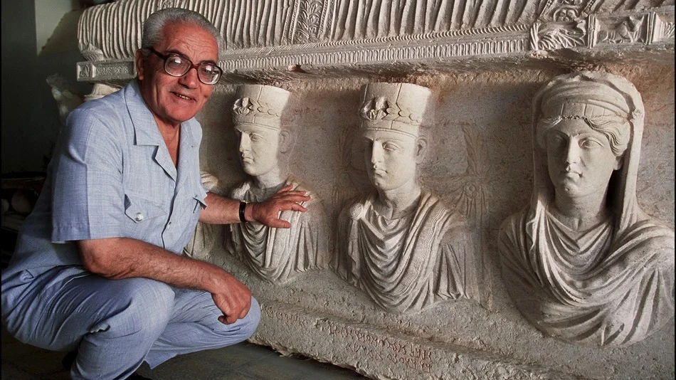 Khaled al-Asaad poses in front of a sarcophagus in Palmyra, Syria, 2002. Photo by Marc Deville.