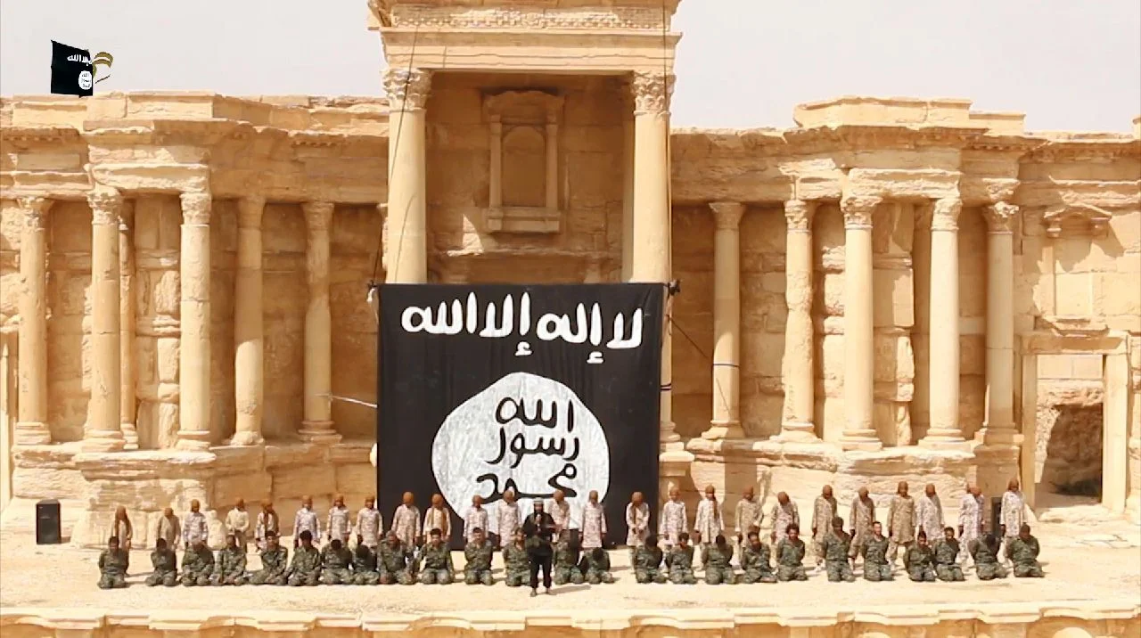 25 Syrian government soldiers kneel in the ancient amphitheatre in the city of Palmyra ahead of being executed by children. Photo by Welayat Homs.