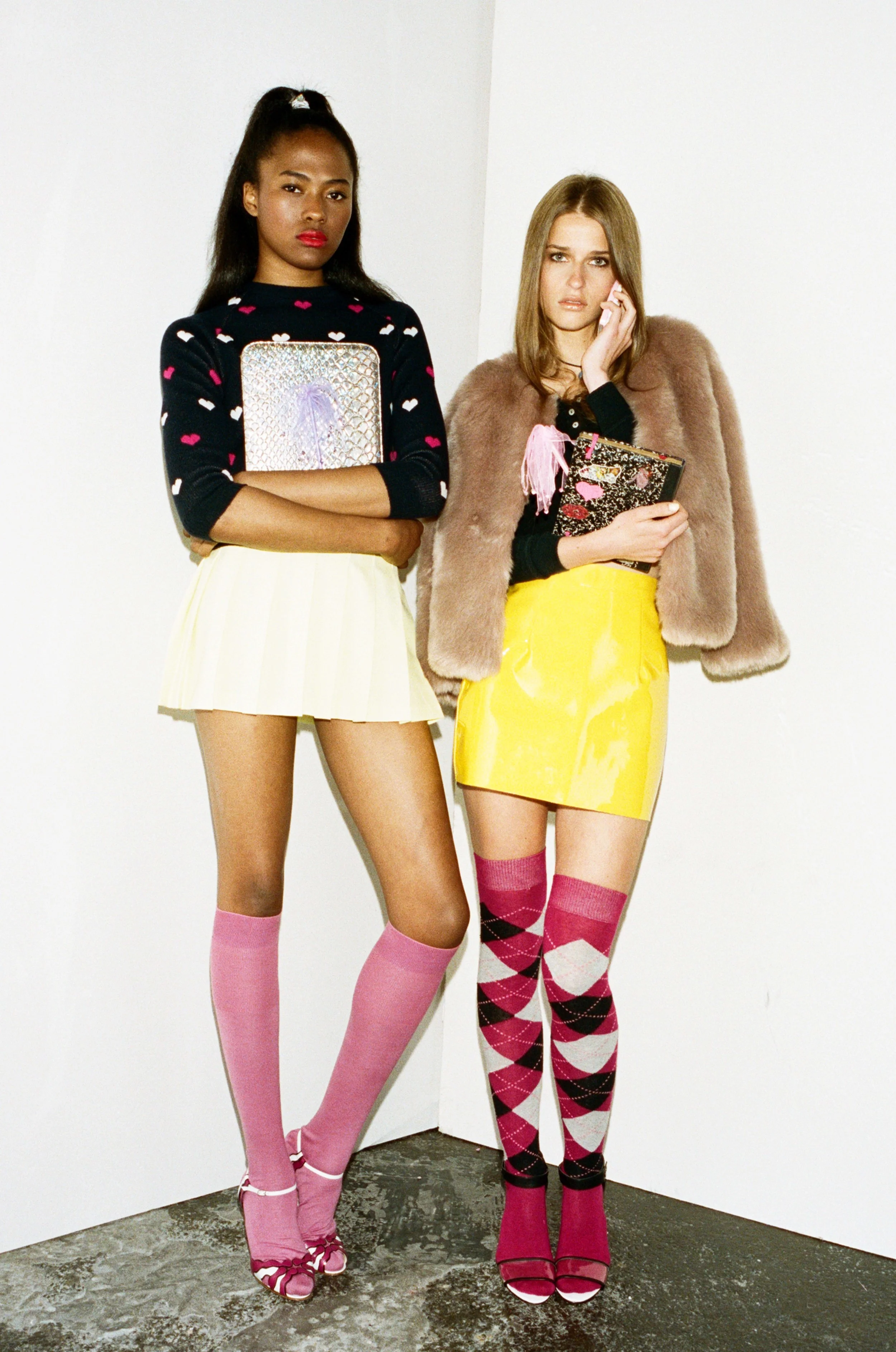 Dominique wears Heart Jumper by Peter Jensen, Yellow Pleat Skirt by American Apparel, Pink Socks by Falke, Heels by Manolo Blahnik. Regitze wears Black Crop Top from Beyond Retro, Yellow PVC skirt by American Apparel, Faux Fur Coat by Warehouse, Socks - Stylist’s Own, Heels by Antipodium