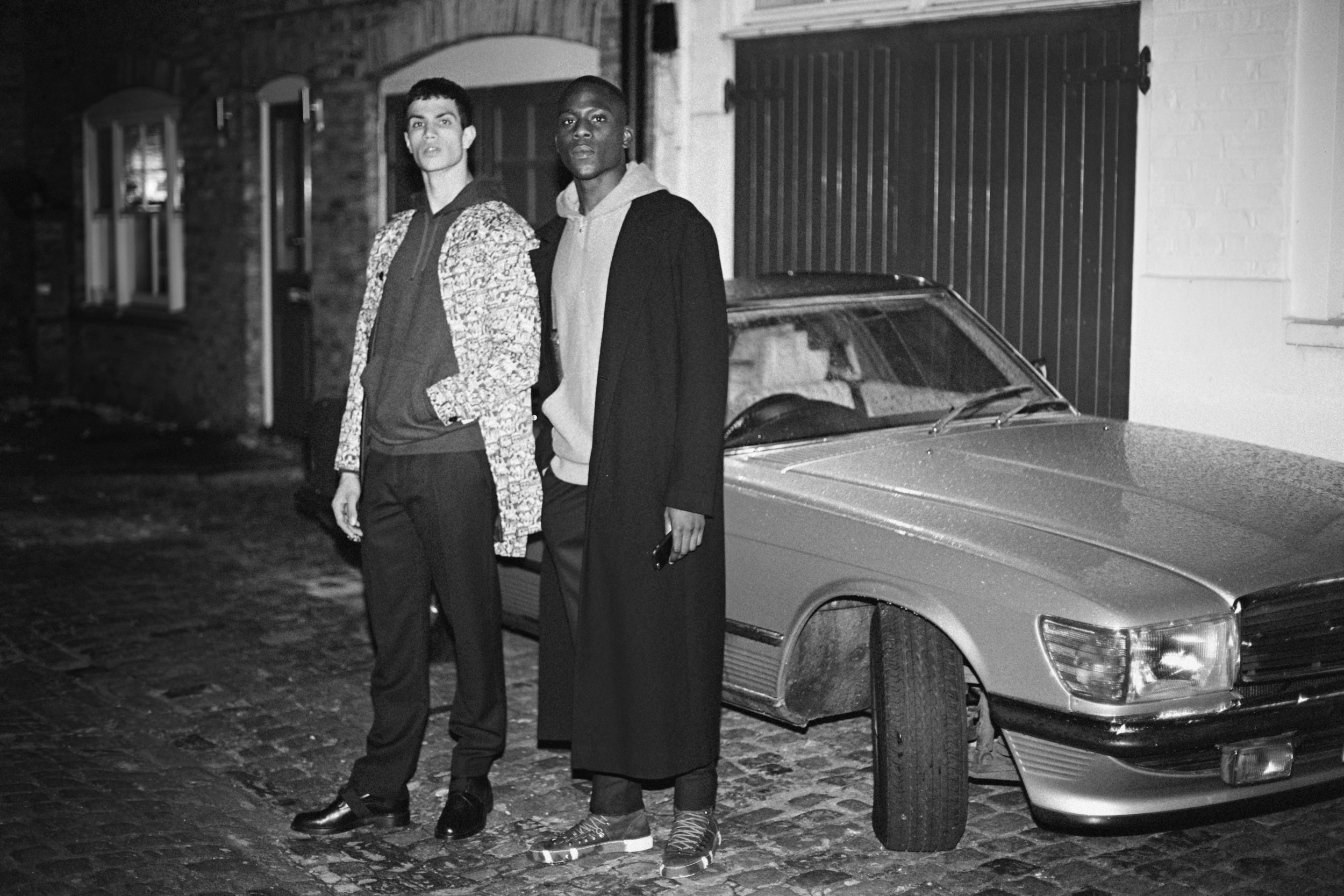 Emmanuel wears Coat by ISSEY MIYAKE MEN , Sweater by Carhartt Wip, Trousers by Christopher Kane and Boots by Swear Ashton wears Jacket by Studio White Label, Sweater by Carhartt Wip, Trousers by Markus Lupfer and Boots by Christopher Kane
