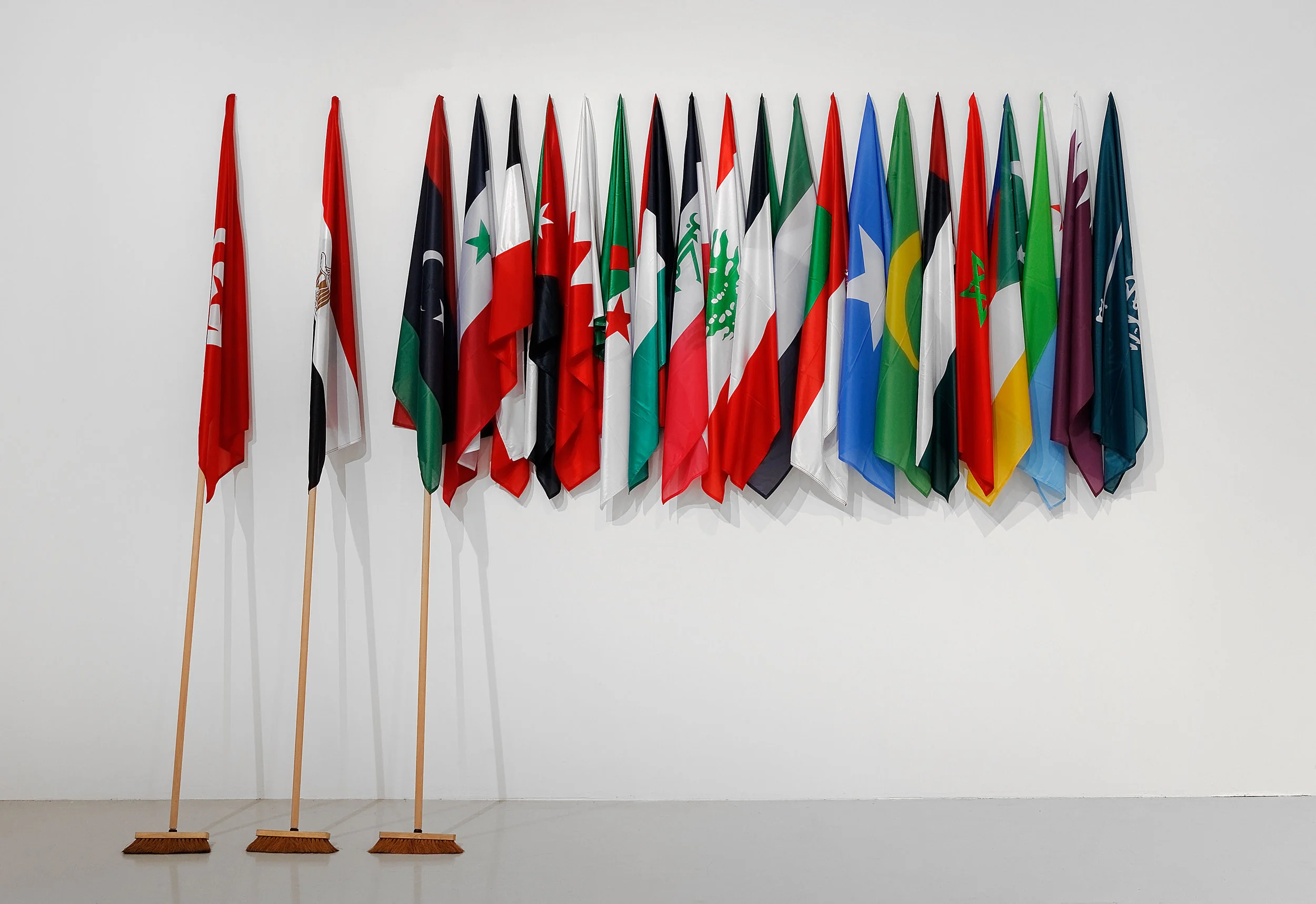 The Lost Springs, October 2011, 3 brooms of 3 meters, 22 flags or arabian countries, 300 x 405 x 40 cm. Courtesy of the artist and Goodman Gallery, Johannesburg-Cape Town. Exhibition view from Le Monde Selon…, FRAC Franche Comté-Besançon, 2015. Photo credit : Blaise Adilon