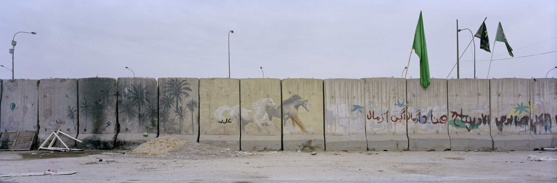 A wall in the Shiite neighbourhood of al-Qahira in Baghdad which separates it from the Sunni neighbourhood of al-Athhamia. The flags are put up for the Shiite holiday of Arbaeen. Iraq; January 2012.