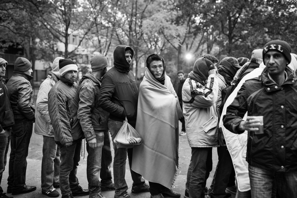 Afghan, Pakistani, and Syrian refugees line up for a warm cup of coffee handed out by volunteers outside the registration center for refugees in Berlin, Germany. October 13, 2015. Photo by Miguel Winograd.