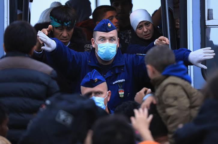A Hungarian police officer tries to prevent refugees from boarding a bus at the refugee camp in Röszke . Photo by Christopher Furlong/Getty Images.