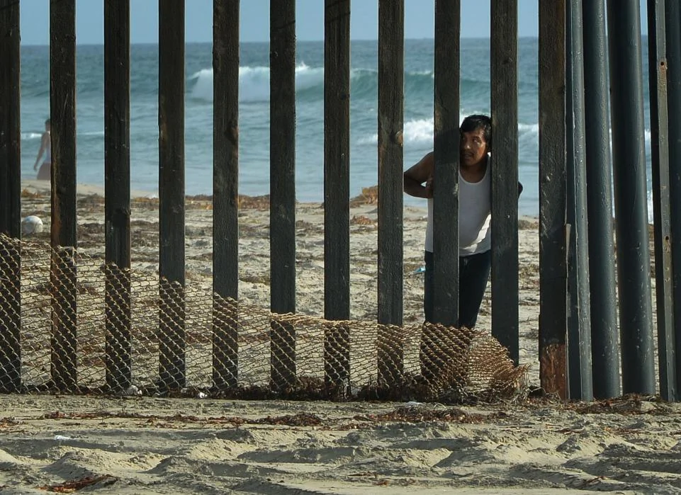 A man looks out toward the U.S. from the Mexican side of the border fence that divides the two countries in San Diego on August 20, 2014. Photo source: Getty Images.