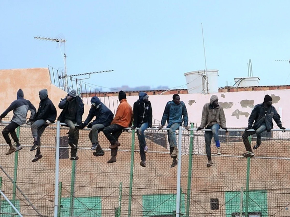 Migrants climbing over the border fence between Morocco and Melilla. Photo source: AFP.