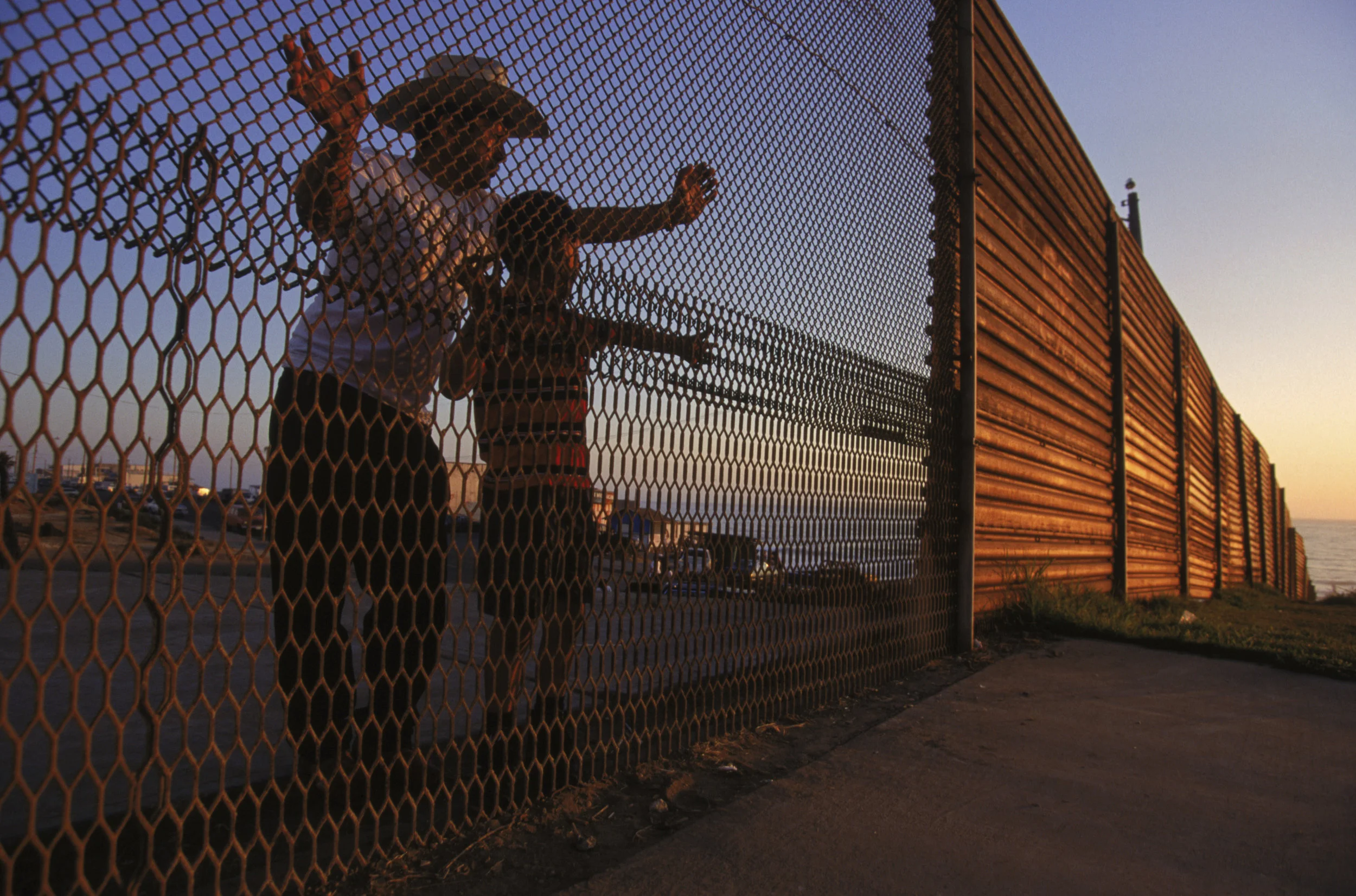 A father and son peer through the international boundary into the United States from Tijuana, Mexico. Photo by Todd Bigelow.