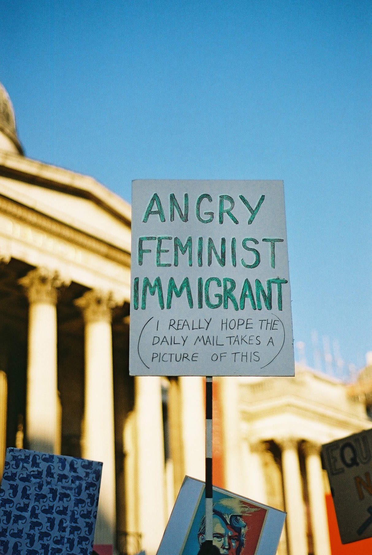A protestor holds a poster with the words "Angry Feminist Immigrant" at the Women's March day in London, 2017. Photo by Camilla Glorioso.