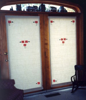 This pair of inside mounted Roman shades have a custom designed applique of Macintosh roses in red and loden.