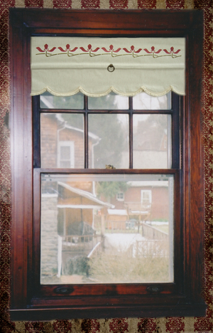 This linen cotton shade has a scalloped edge with matching gimp. The Iris border is in red and loden. It is front roll for a finished look.