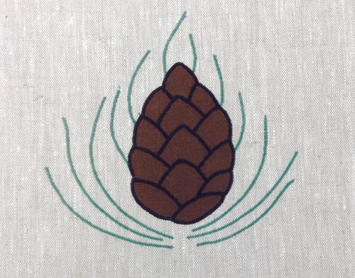 Pine Cone : A medallion that can be turned at at45 degree angle to become a corner motif,shown here in brown, black and sage, 6 1/2" from bottom to highest needle, $35.00 per motif.