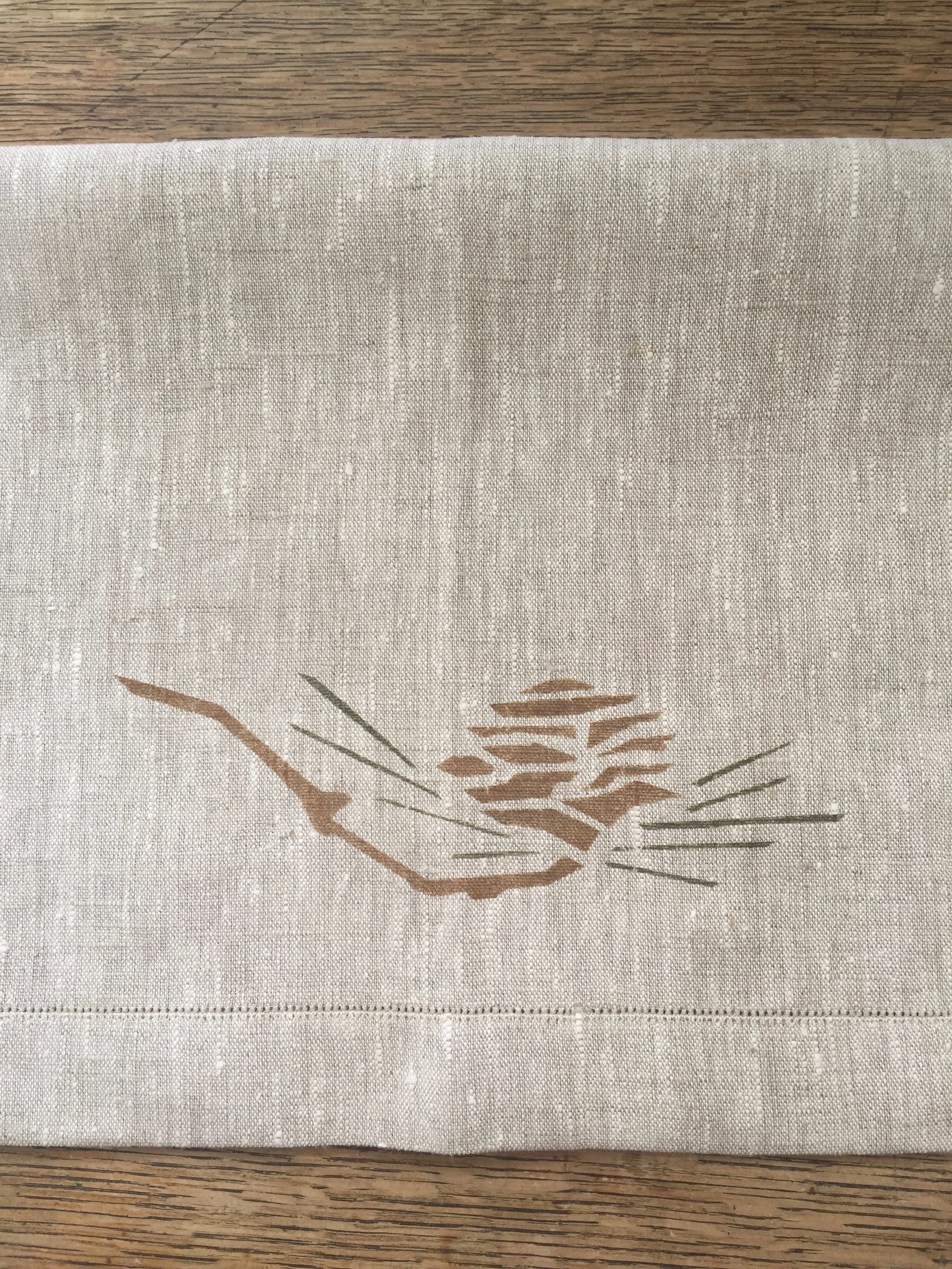 Pine Cone Two Border stencil. A popular motif in whiskey and loden on a custom napkin with pin stitch hem. 