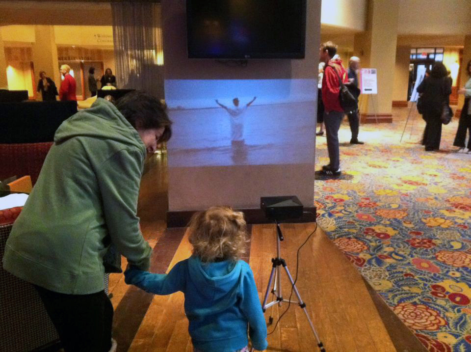 Passers-by watch the festival videos in the lobby of the Sheraton Hotel in Washington, D.C.