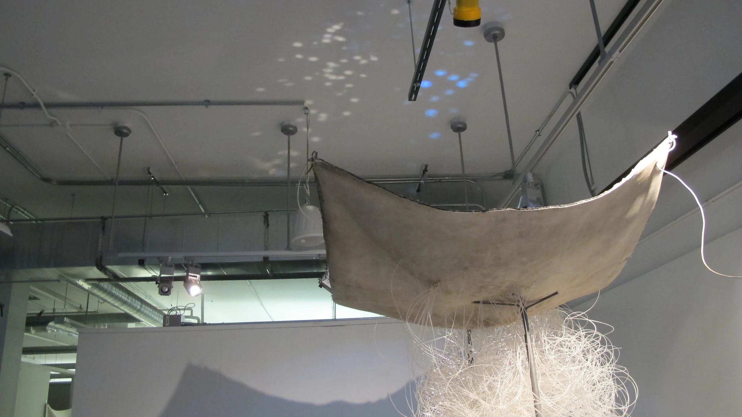   With The Stars Above and The Sun Below   2016  cement cloth, steel, plastic filament, search lights  6 x 4 x 10 ft     using the search for relatives as a starting point, this work aims to present the ideal vs real focus that comes when searching f