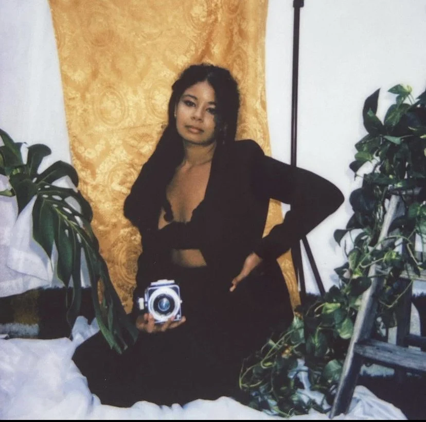 woman of color with Hasselbald 120mm film camera posing with plants