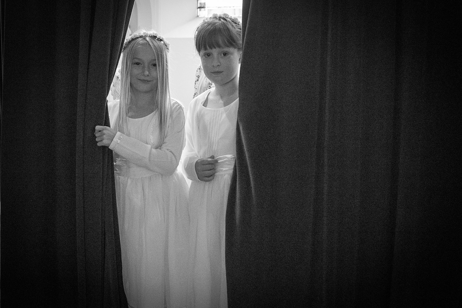 Flowers girls peeking from behind a curtain at wedding ceremony in Harrogate