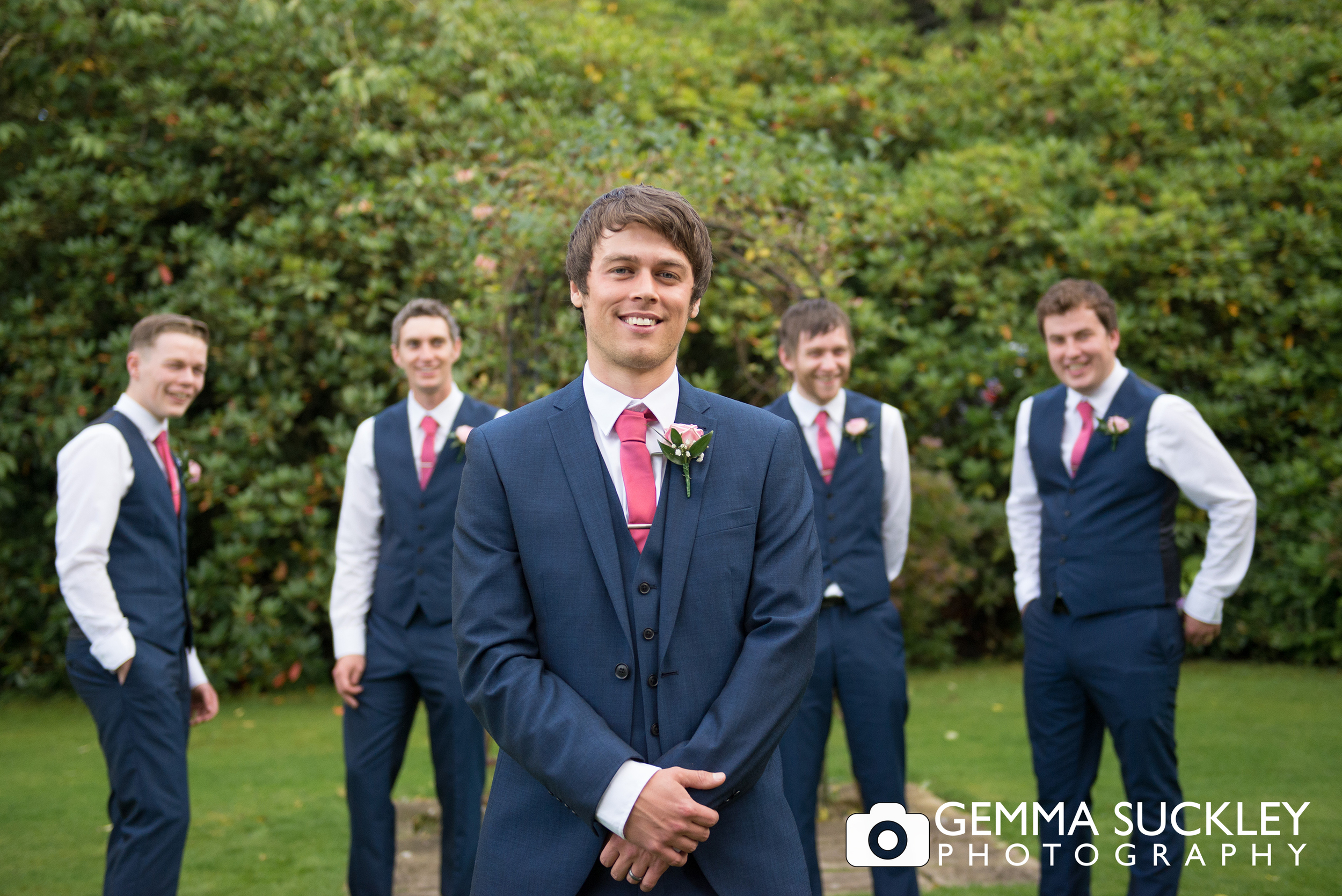 the groom and groom's party wearing pink buttonhole flowers