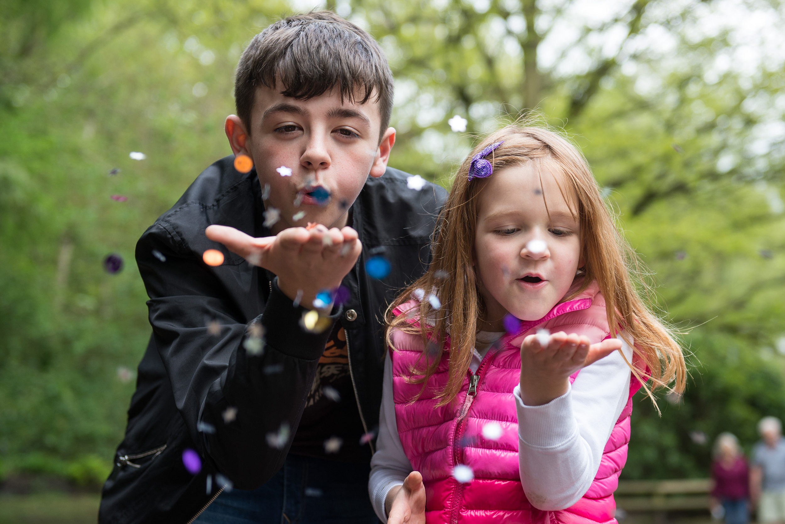 Brother and sister blowing glitter in golden acre park
