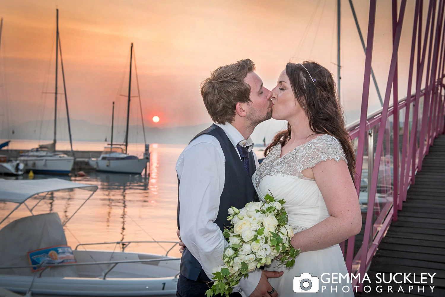 bride and groom kissing as the sun sets in lake garda