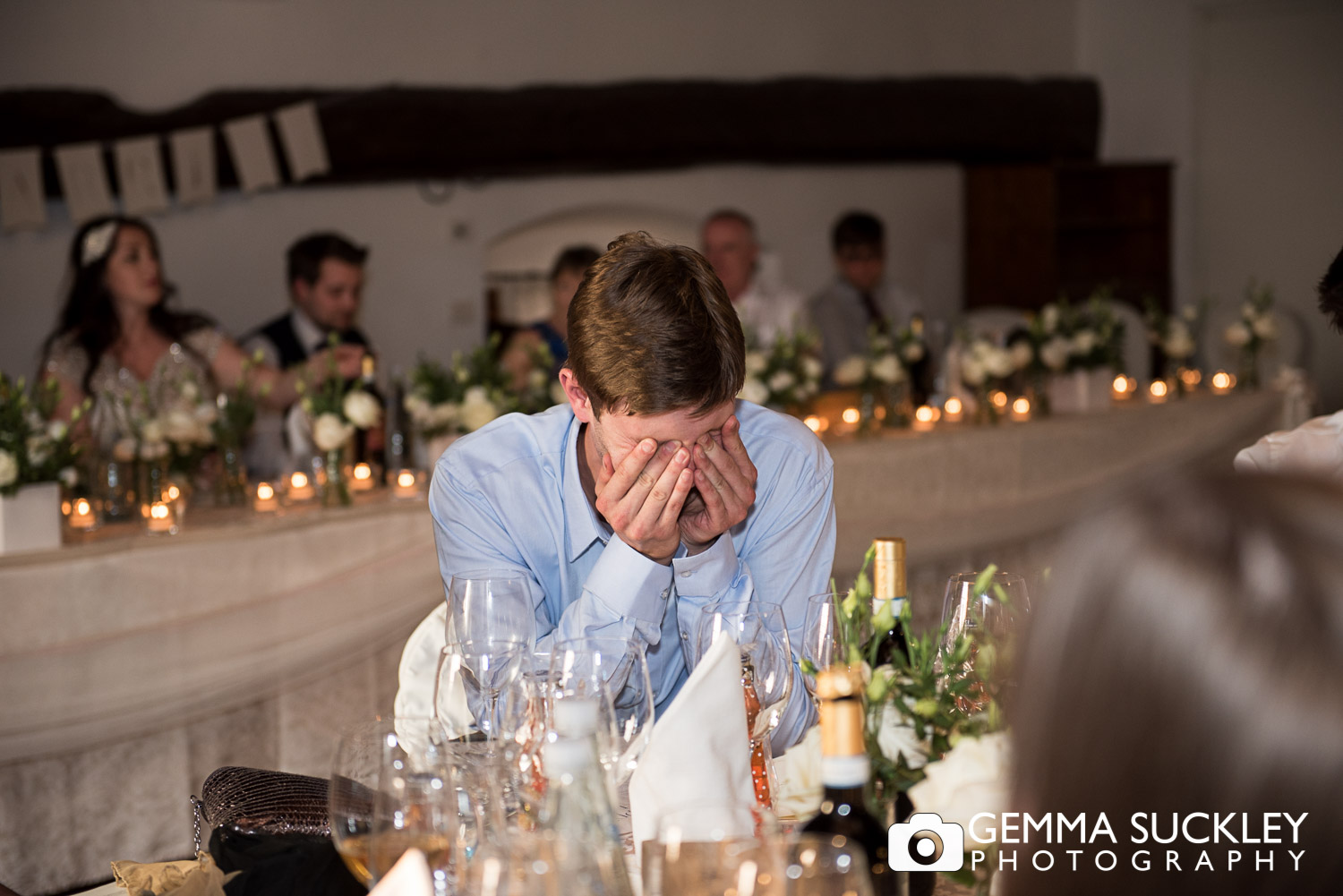 Wedding guest covering his face laughing during wedding sppeches