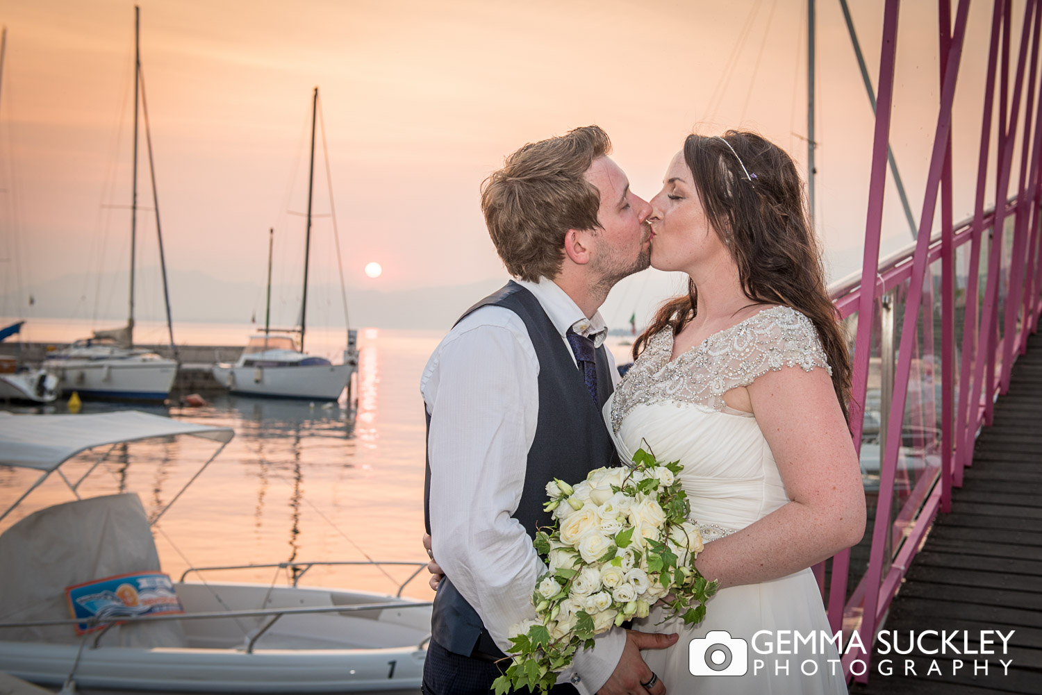 Bride and groom kissing as the sun sets on Lake Garda