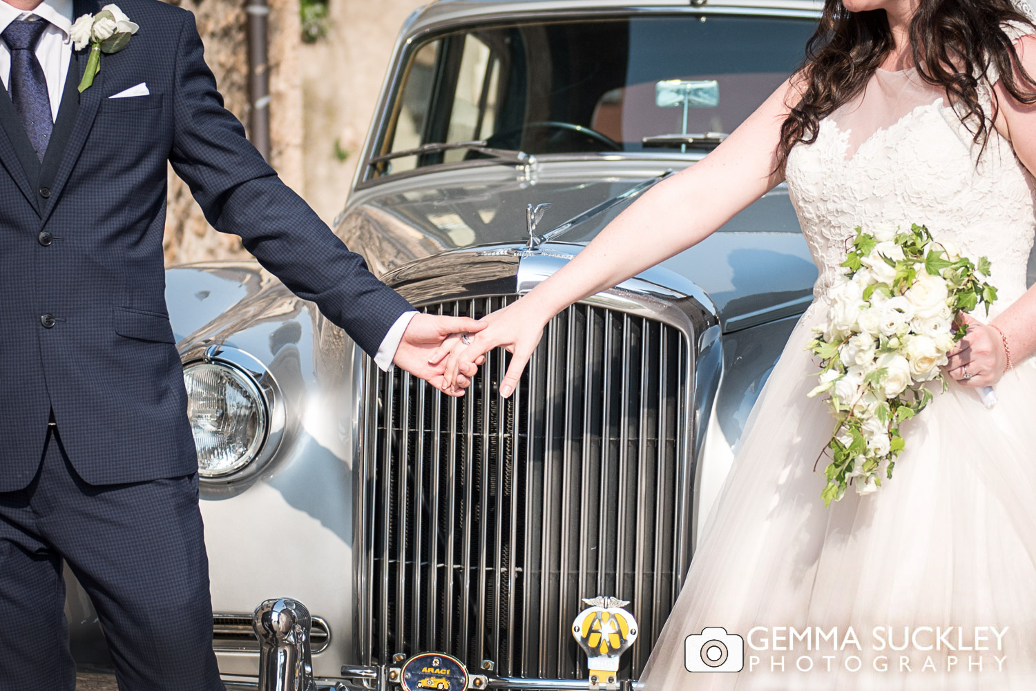 bride and groom posing with wedding car