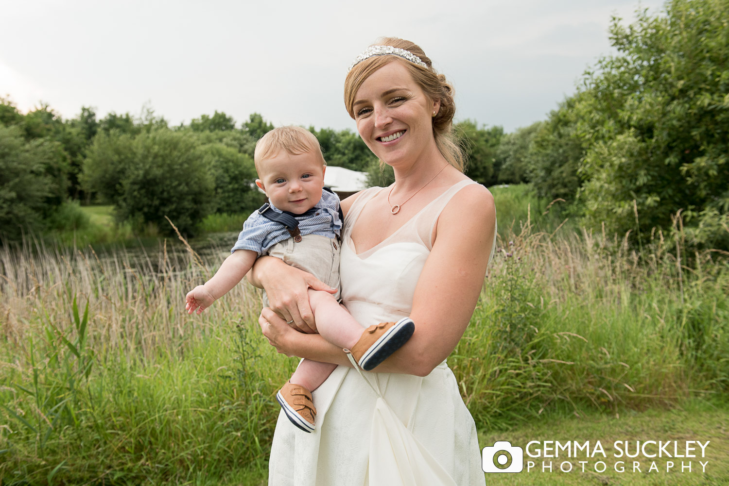 Bride holding her baby with the lake view at oaklands in east Yorkshire