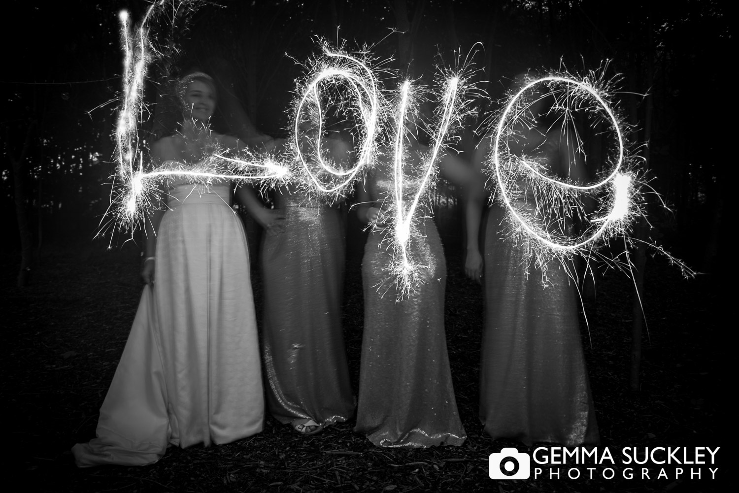 bride and bridesmaid writing love with wedding sparklers 