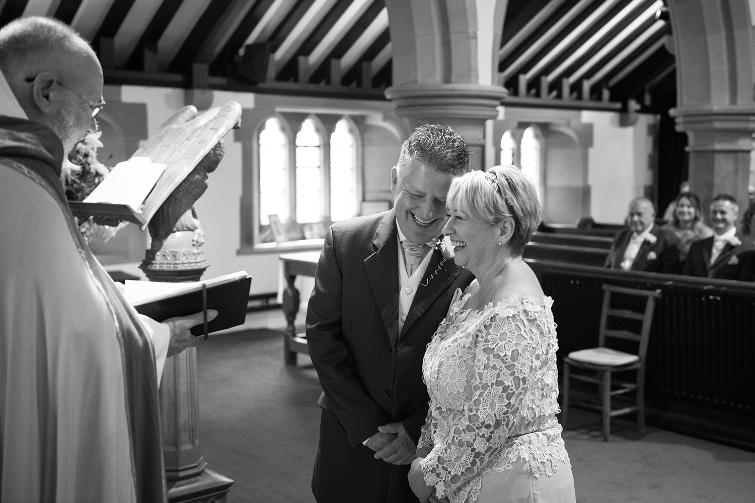 bride and groom giggling stood in front of the vicar at their wedding ceremony