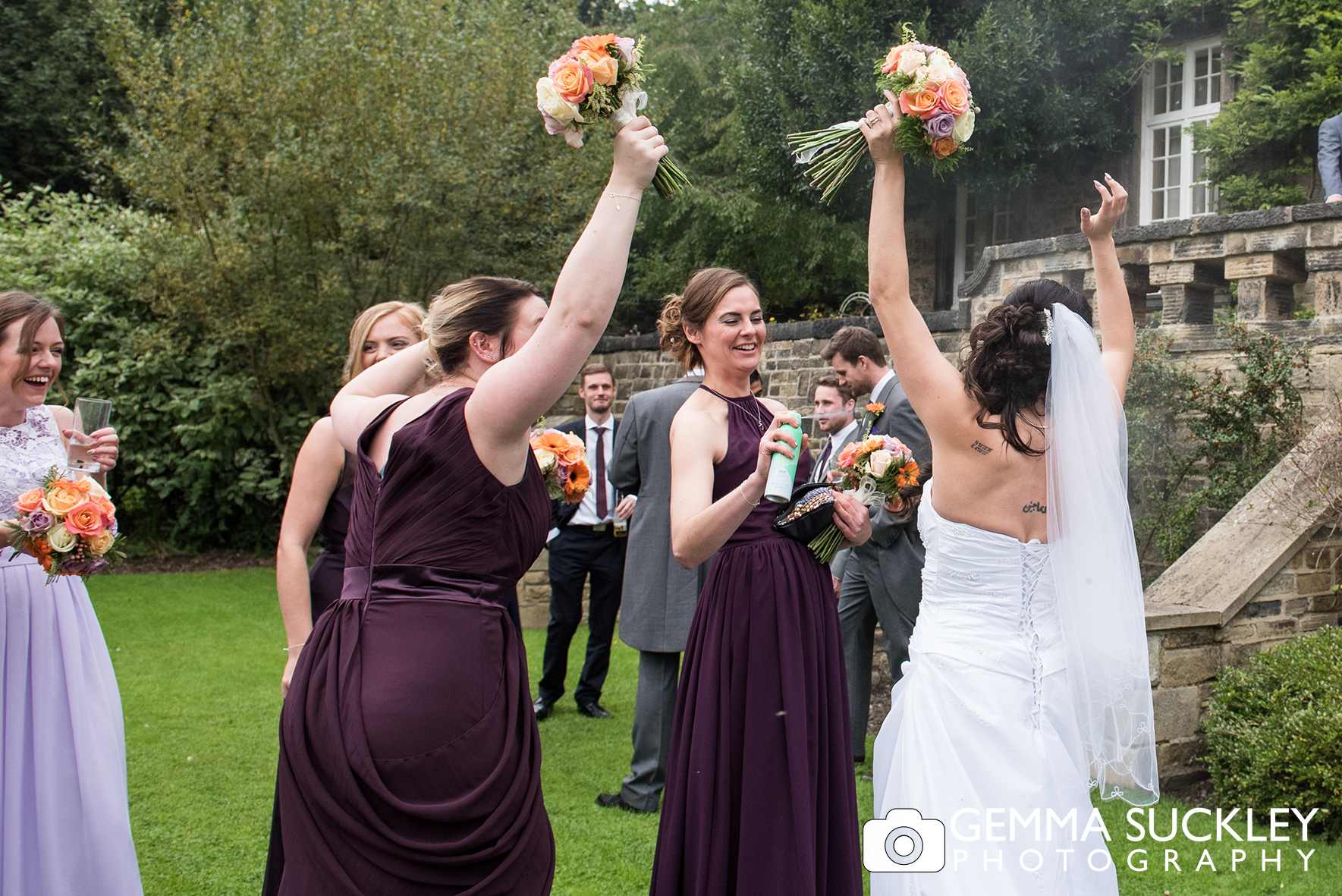 bride and bridesmaids at outdoor wedding spaying deodorant 