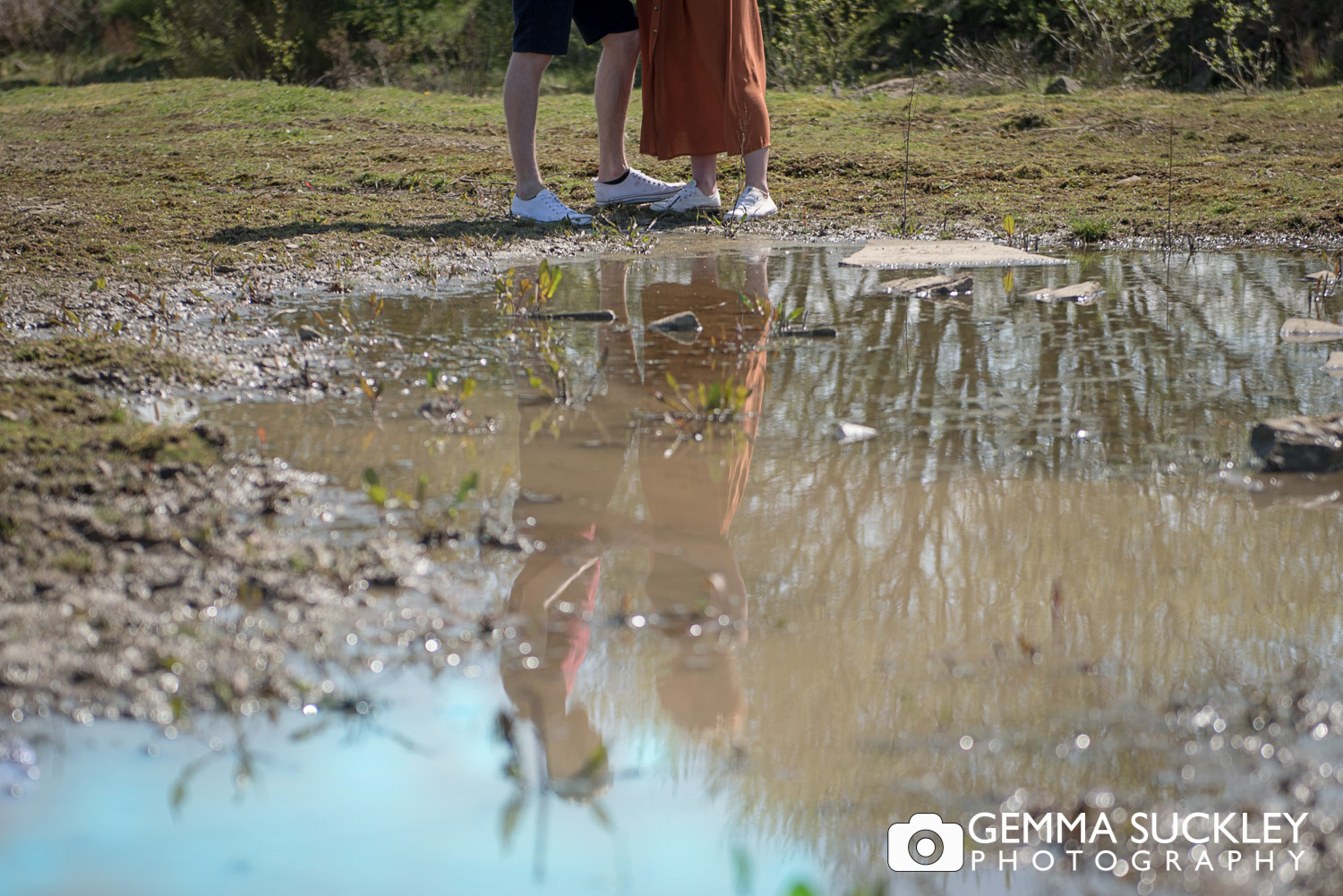 couples feet reflecting in a puddle
