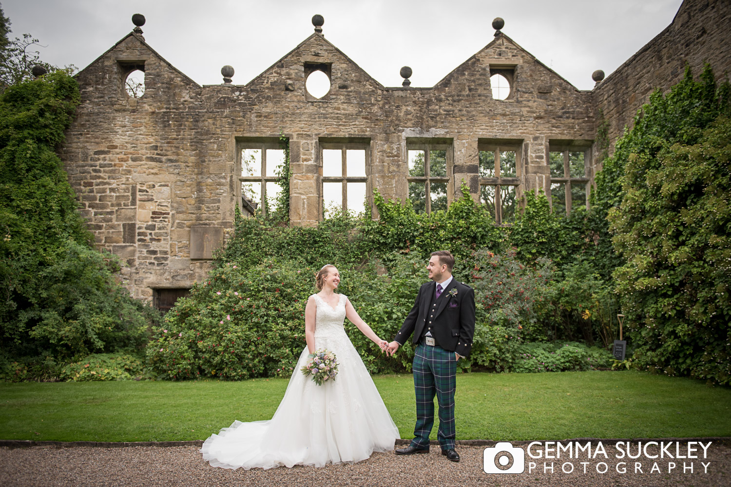 bride and groom holding hands in front of the ruin at east riddlesden hall