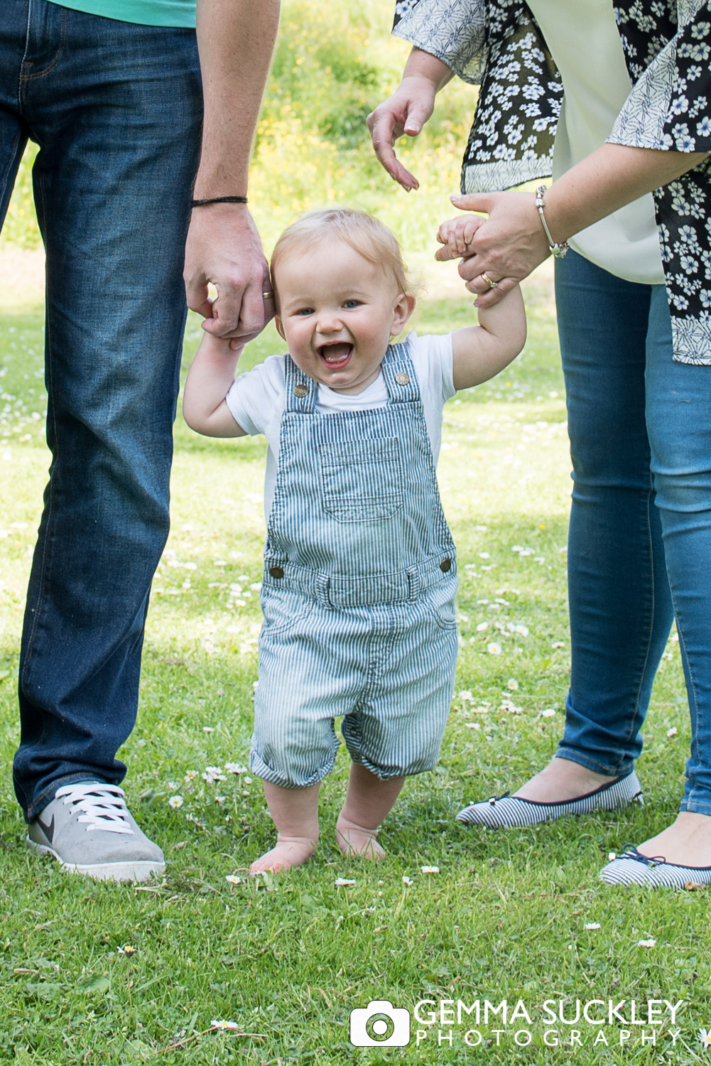 baby boy giggling holding his mum and dads hand during a family photo shoot in skipton 