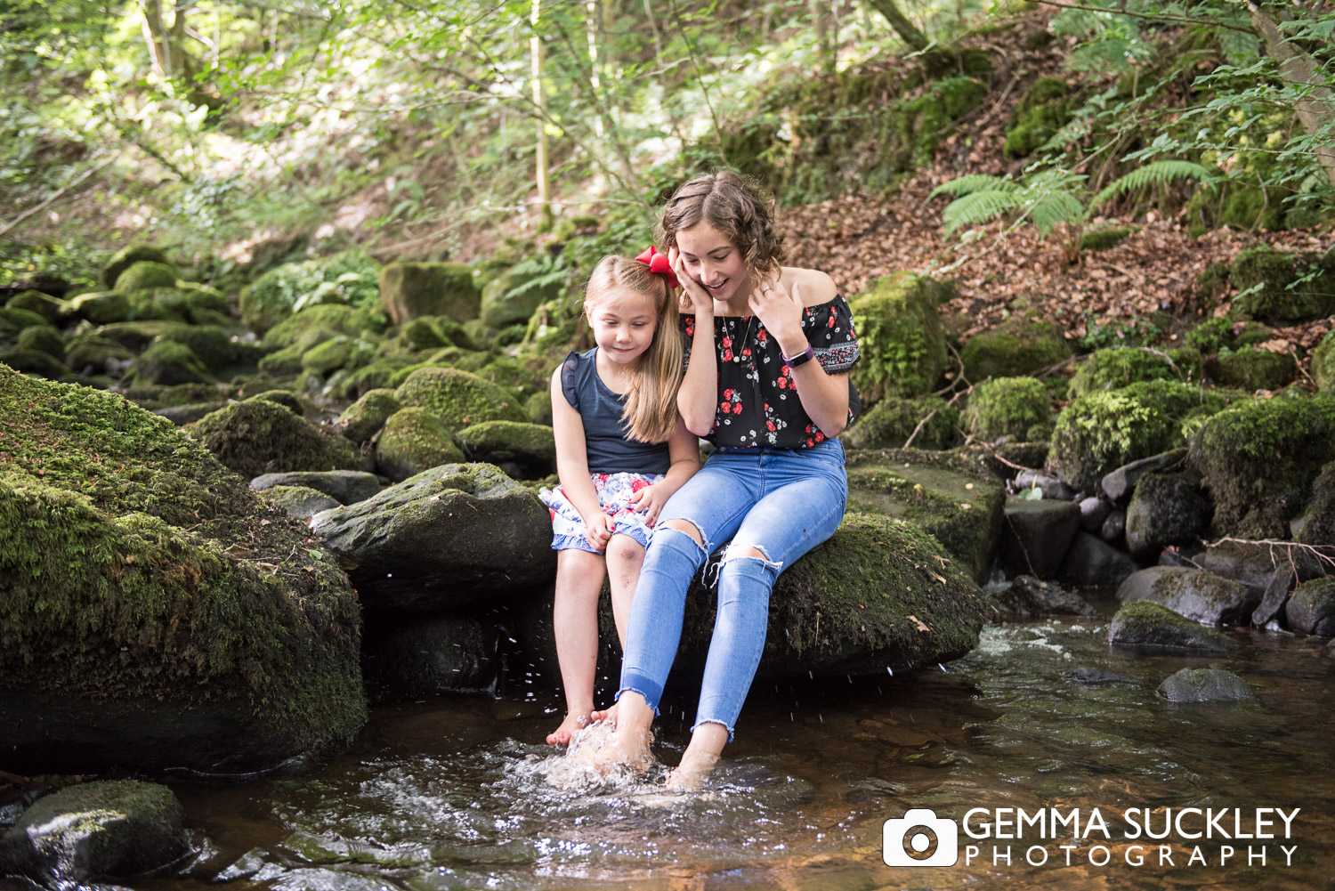 sister dipping their feet in a stream in sutton in craven during their lifestyle photo shoot