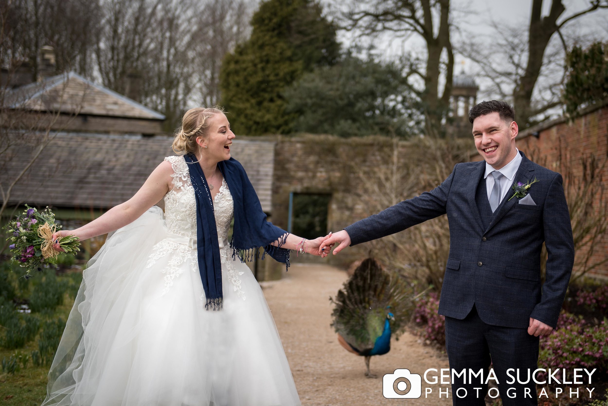 bride and groom at brought hall with a peacock beind them