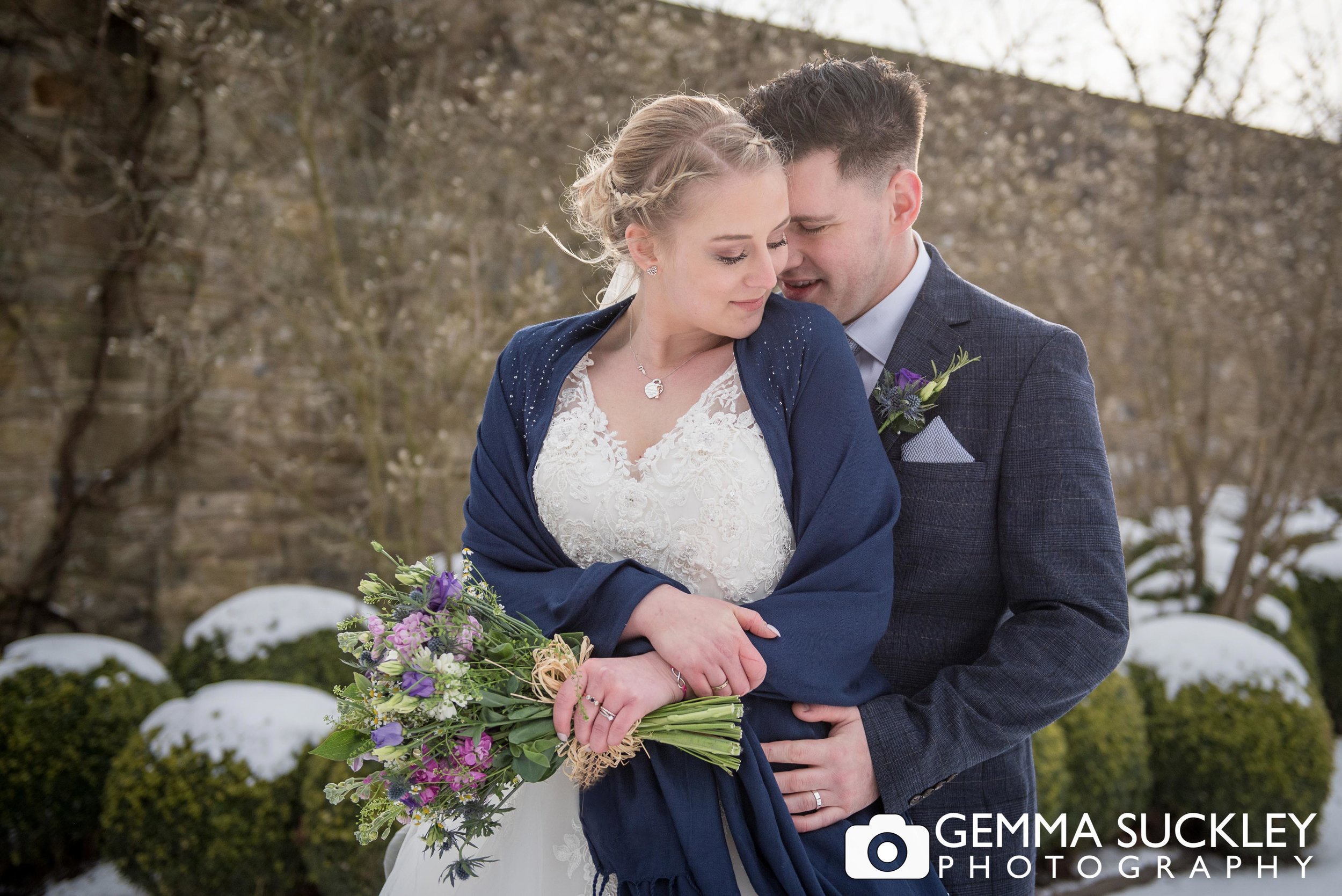 bride and groom hugging in the snow at broughton hall