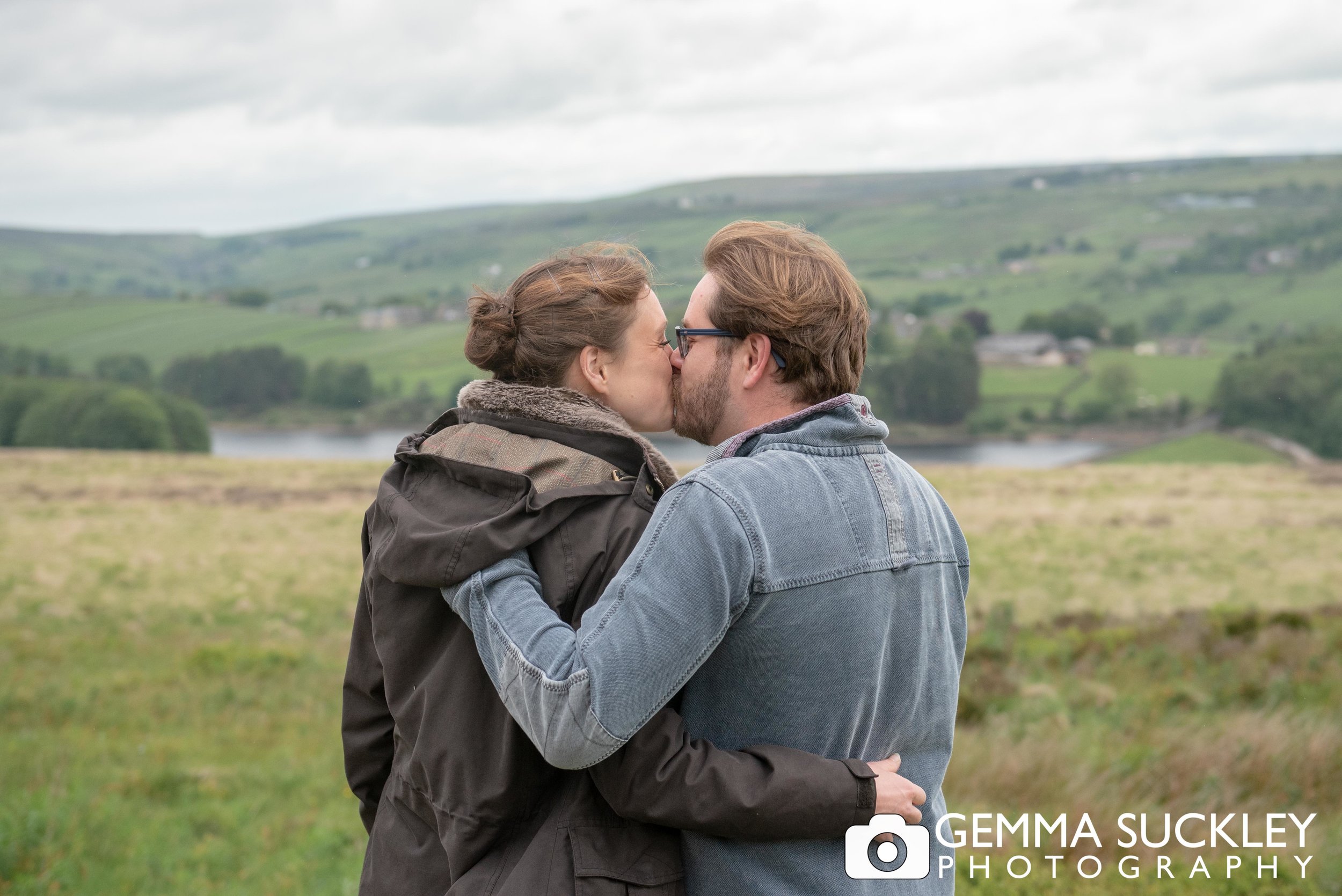 brife and groom to be kissing with haworth moor in the background