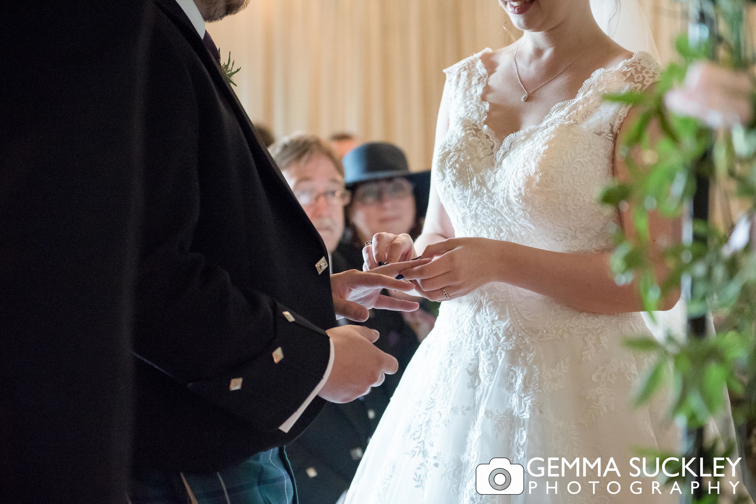 groom placing the ring on his bride's finger