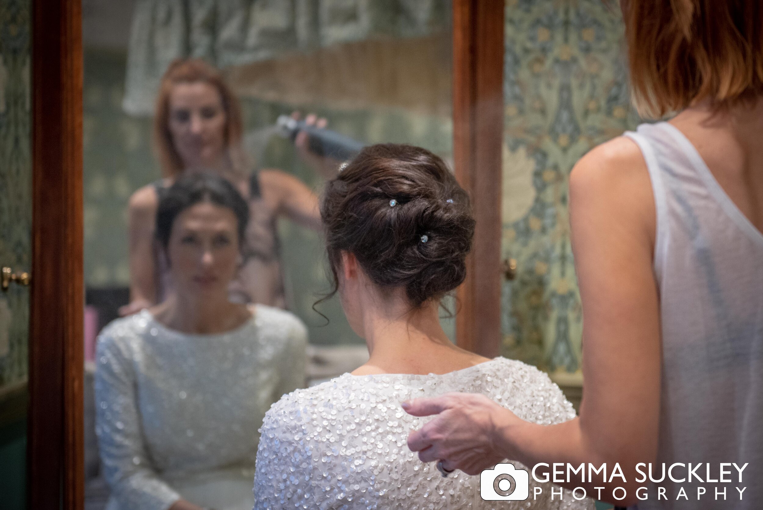 bride looking in the mirror whilst getting hair done