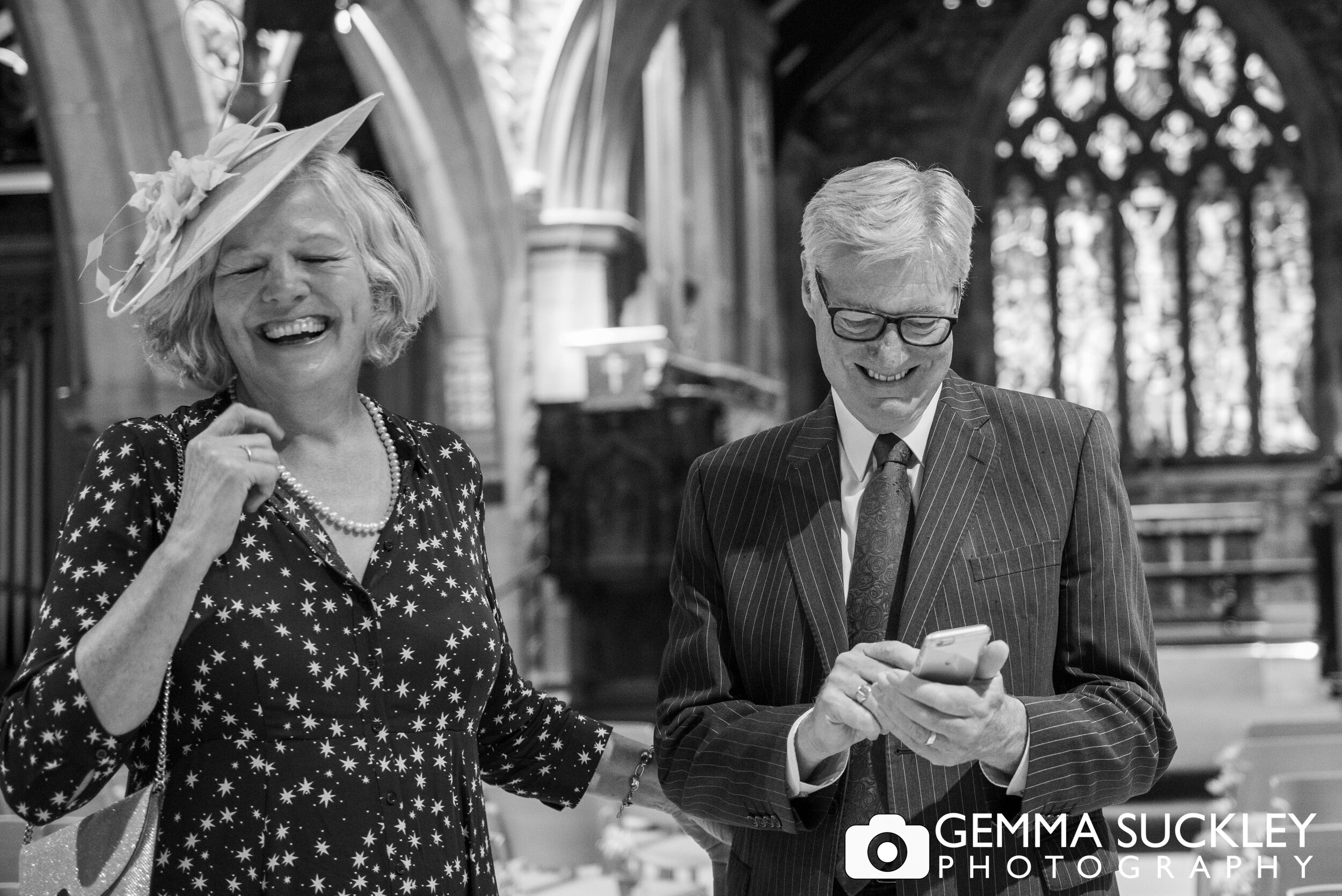 a natural black and white photo of wedding guests lauging