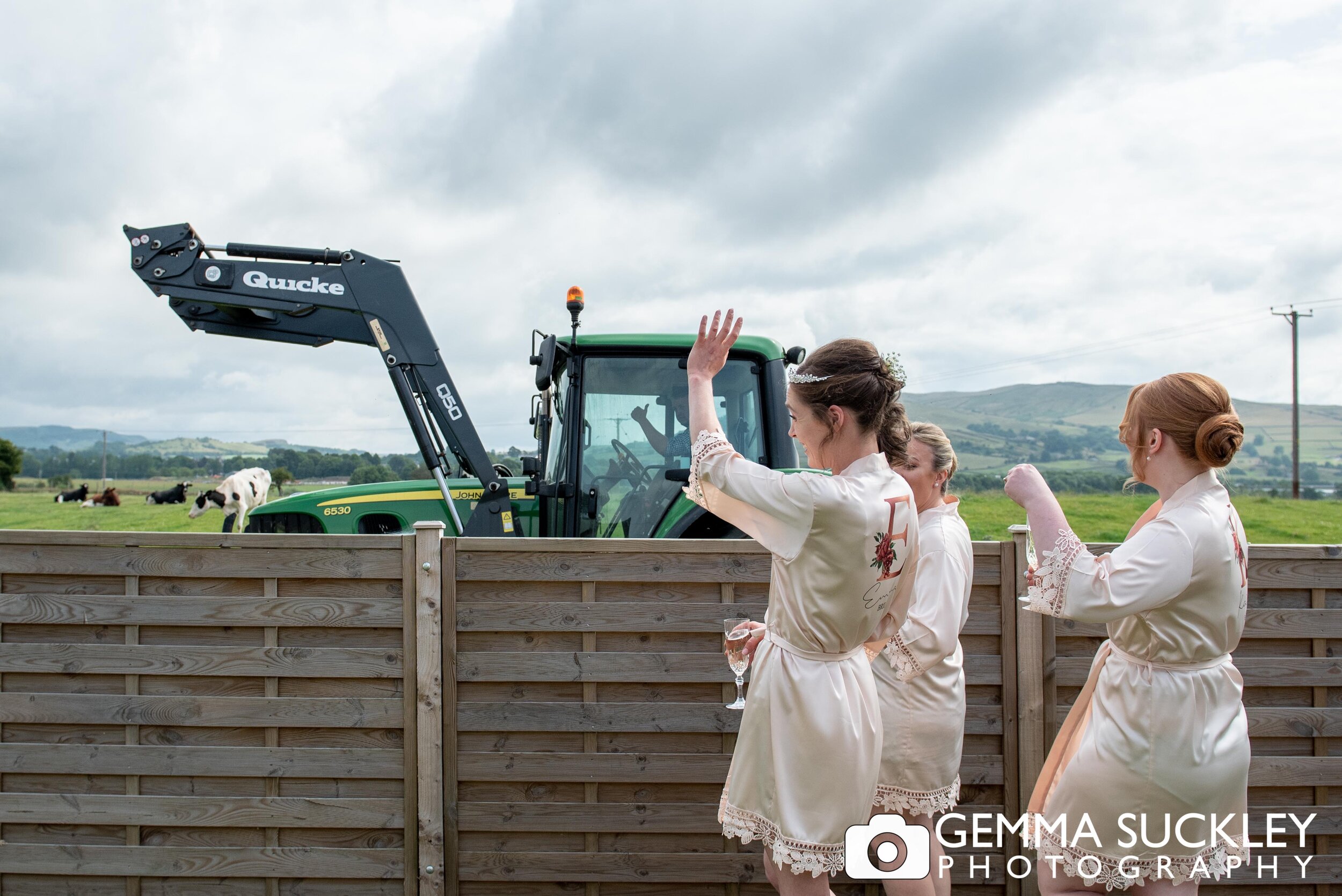 bride and bridesmaids waving at s farmer passing in a tractor