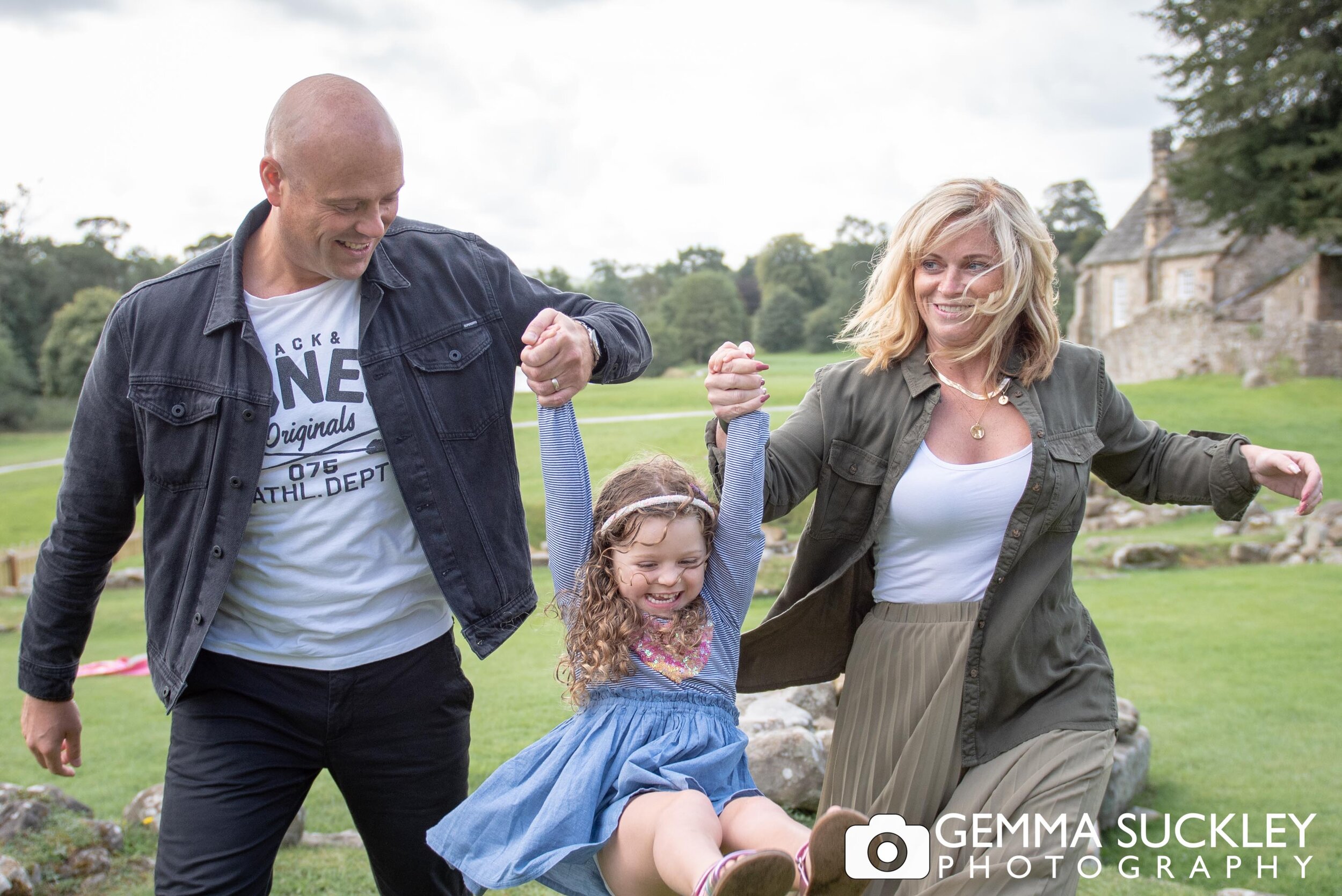 mum and dad swinging their daughter during a family photo shoot at bolton abbey