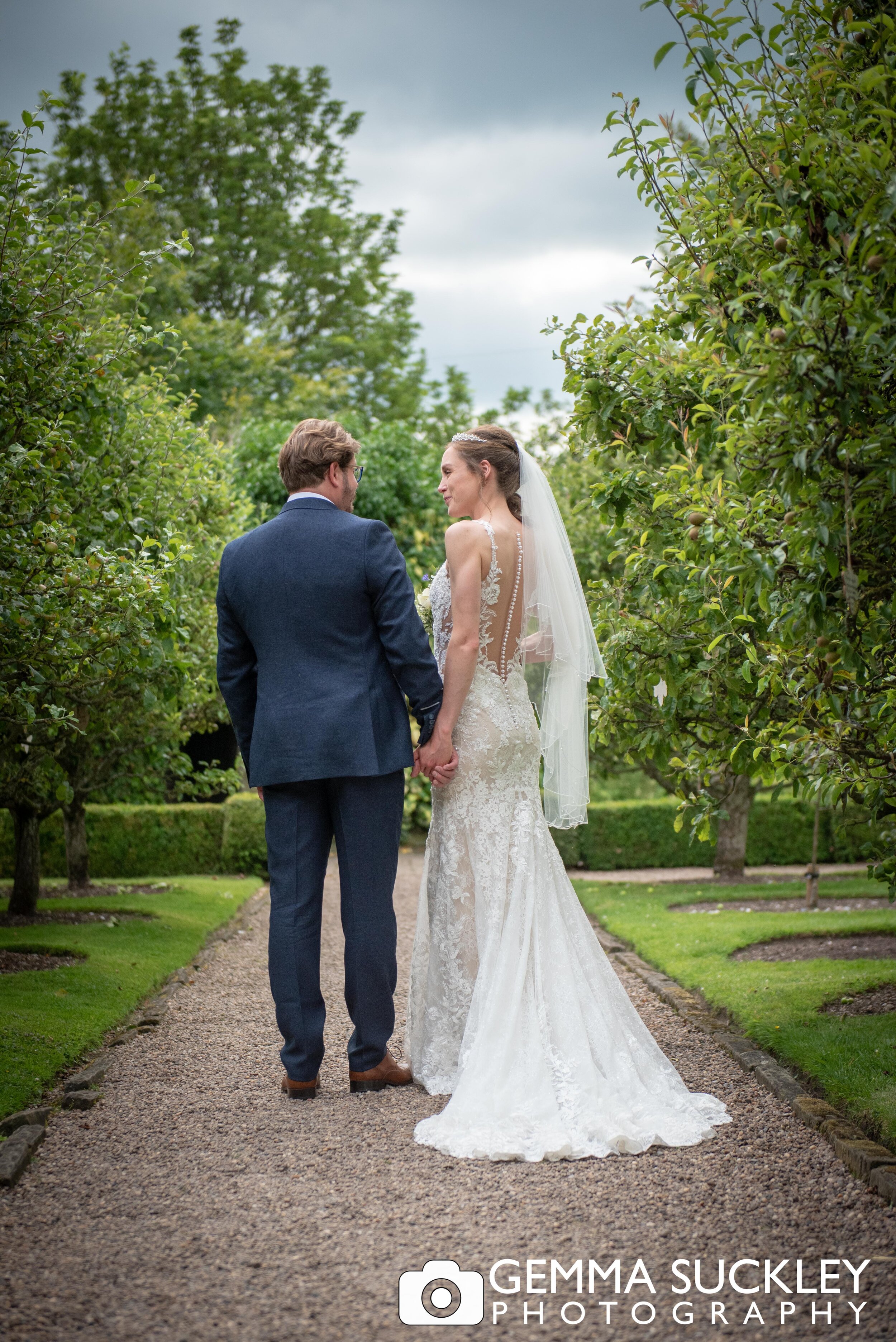 bride and groom walking through the gardens at east riddlesden hall