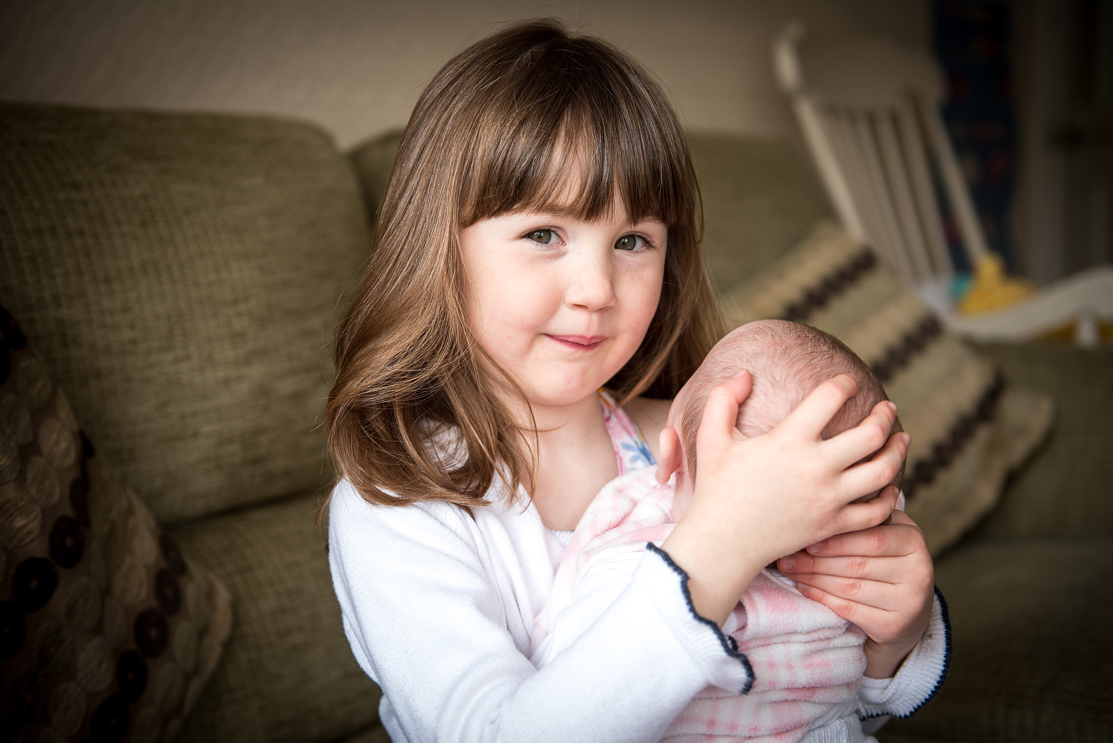 A little girl hugging her new born sister for a family photo shoot